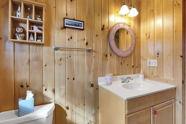 bathroom with wooden walls, toilet, and vanity