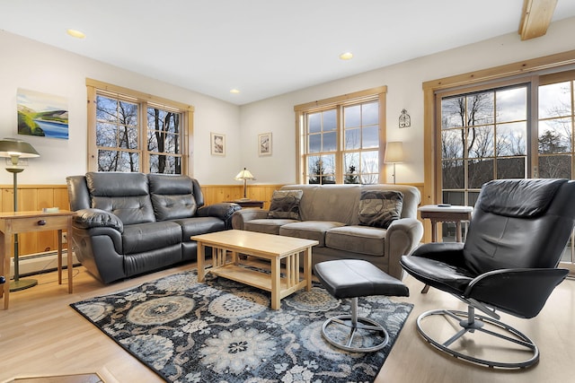 living room featuring beamed ceiling, wood walls, light wood-type flooring, and a baseboard heating unit