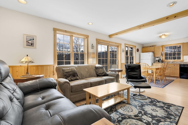 living room featuring light wood-type flooring, a wainscoted wall, recessed lighting, and beam ceiling