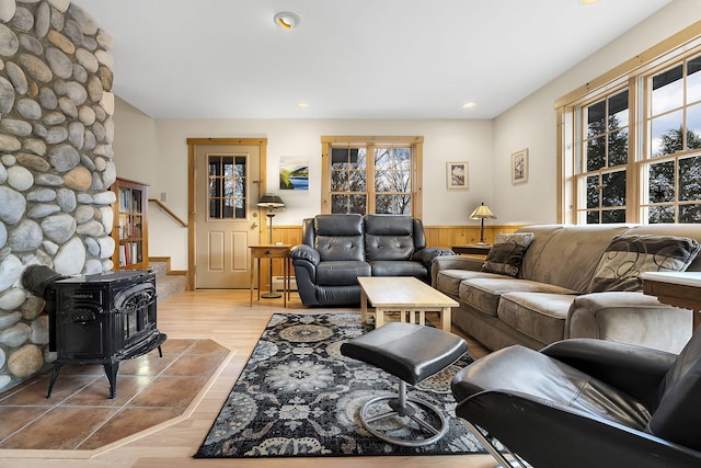 living room featuring wainscoting, stairs, a wood stove, and light wood-style flooring