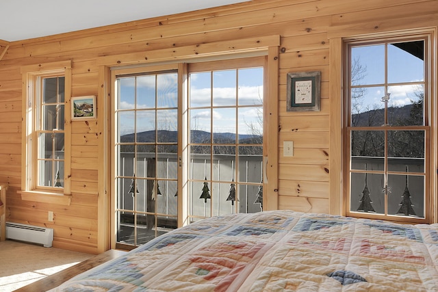 bedroom featuring a baseboard radiator, wood walls, a mountain view, multiple windows, and carpet