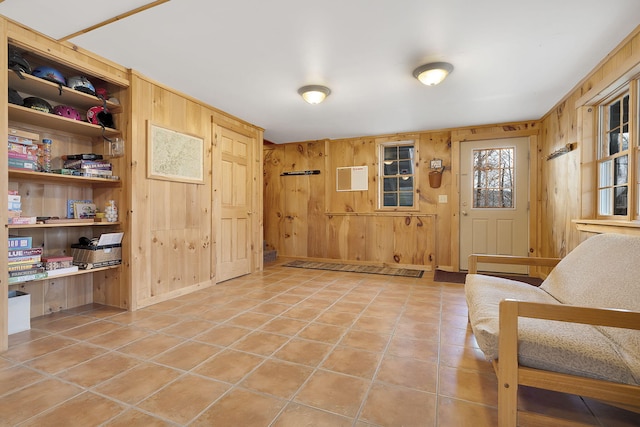 living area with tile patterned floors and wooden walls