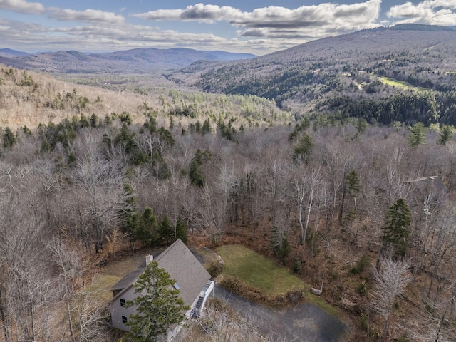 aerial view of property's location with a mountain backdrop and a heavily wooded area