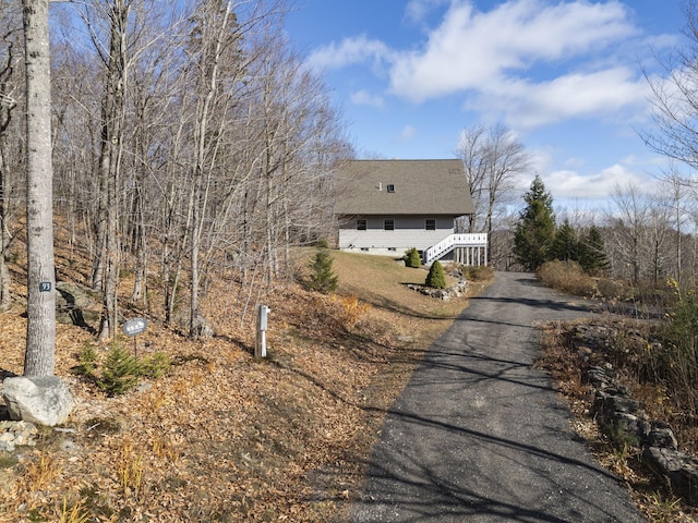 view of property exterior featuring asphalt driveway and stairway