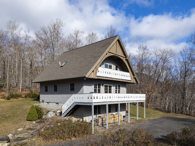 view of front of house with stairs, a shingled roof, a front lawn, and a deck