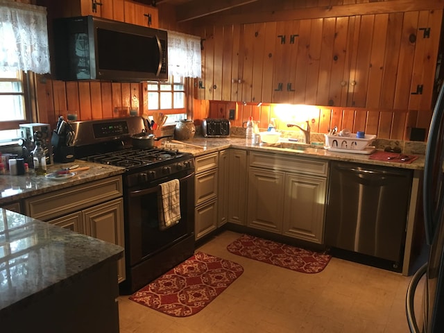 kitchen featuring appliances with stainless steel finishes, a healthy amount of sunlight, sink, and stone countertops