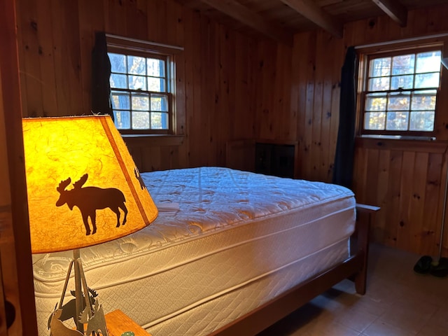 bedroom featuring beam ceiling and wood walls