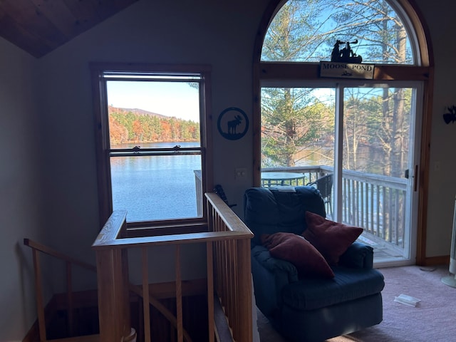 carpeted dining space with a water view and lofted ceiling