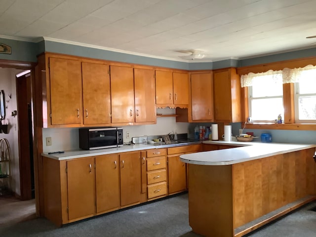 kitchen with kitchen peninsula, dark colored carpet, sink, and crown molding