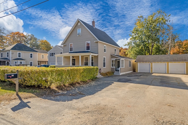 view of property featuring covered porch, an outdoor structure, and a garage