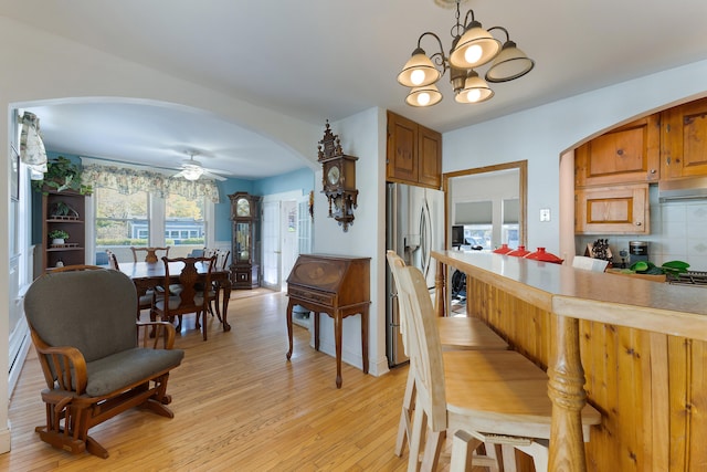 kitchen featuring decorative backsplash, stainless steel fridge with ice dispenser, ceiling fan with notable chandelier, and light hardwood / wood-style floors