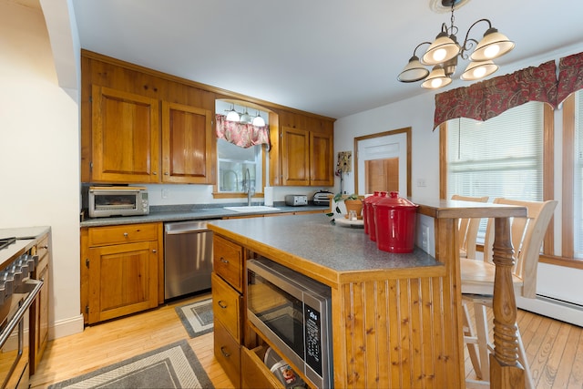 kitchen with a kitchen island, light hardwood / wood-style floors, stainless steel appliances, decorative light fixtures, and an inviting chandelier