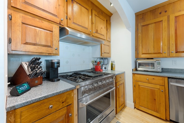 kitchen featuring stone countertops, stainless steel appliances, tasteful backsplash, and light hardwood / wood-style flooring