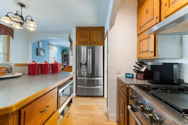 kitchen with appliances with stainless steel finishes, a notable chandelier, decorative light fixtures, and light hardwood / wood-style floors