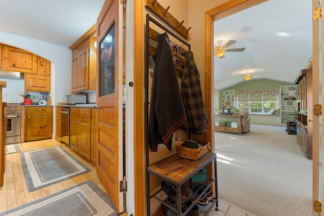 kitchen featuring decorative backsplash, light hardwood / wood-style flooring, stainless steel appliances, vaulted ceiling, and ceiling fan