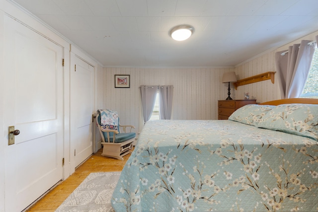 bedroom featuring multiple windows, ornamental molding, and light hardwood / wood-style flooring