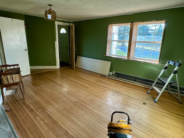 interior space featuring a baseboard heating unit, a textured ceiling, and light hardwood / wood-style floors