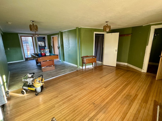 playroom with ornamental molding, a textured ceiling, and wood-type flooring