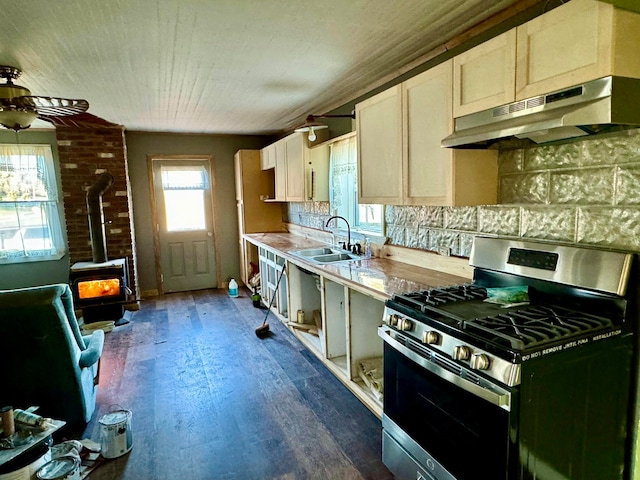 kitchen featuring tasteful backsplash, sink, a wood stove, ceiling fan, and gas range