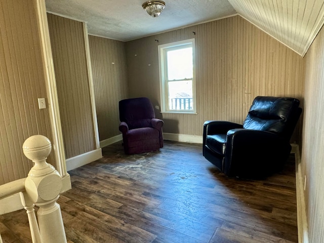 living area featuring dark hardwood / wood-style floors, wooden walls, and vaulted ceiling