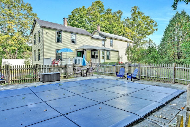 back of property with fence, a chimney, and a patio area