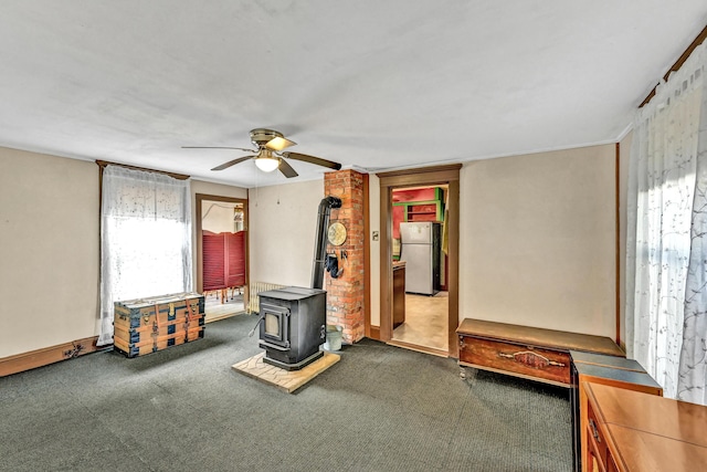 unfurnished living room with a wood stove, a ceiling fan, and healthy amount of natural light