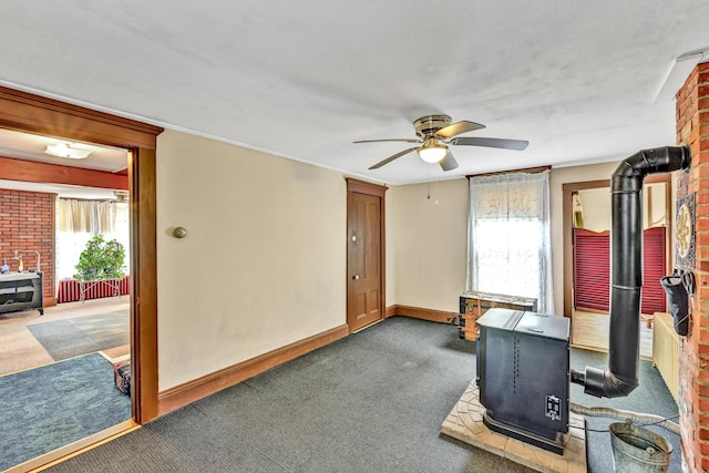 exercise area featuring a wood stove, carpet, a ceiling fan, and plenty of natural light