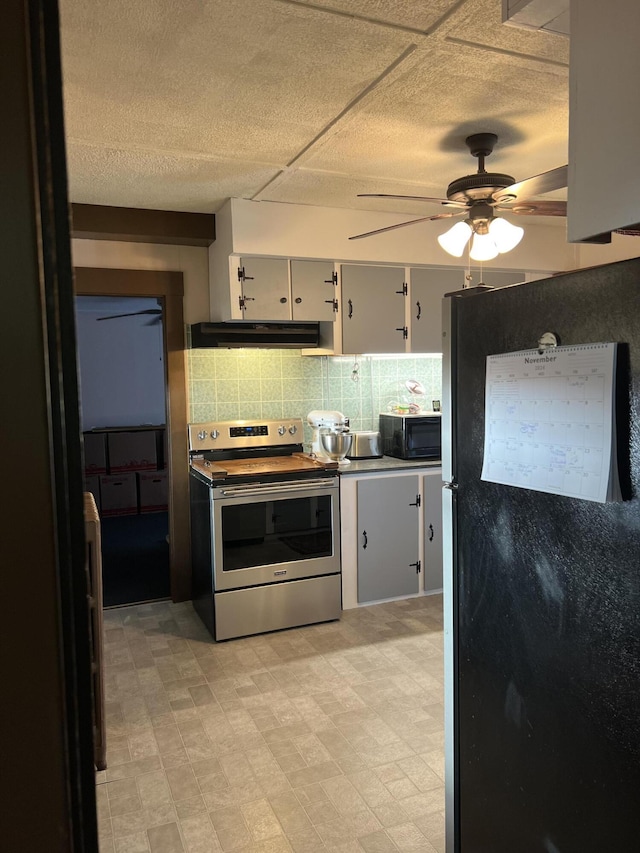 kitchen featuring stainless steel appliances, under cabinet range hood, a ceiling fan, light floors, and decorative backsplash