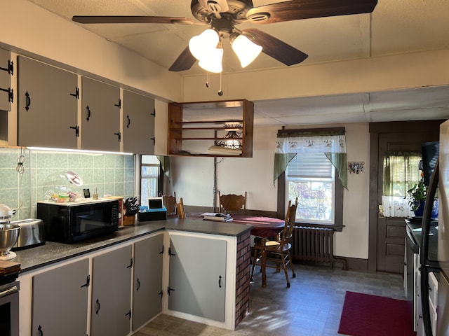 kitchen with black microwave, radiator, dark countertops, tile patterned floors, and decorative backsplash