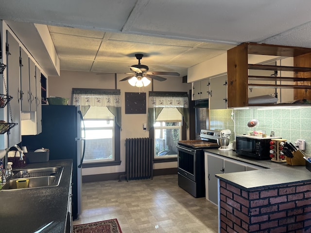 kitchen featuring stainless steel range with electric cooktop, radiator heating unit, black microwave, a sink, and tasteful backsplash
