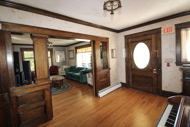 foyer entrance featuring a baseboard radiator, ornamental molding, ornate columns, and hardwood / wood-style flooring