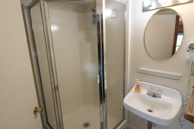 bathroom with a shower with shower door and sink