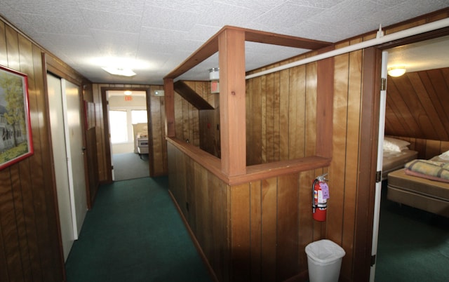 corridor featuring wooden walls and carpet flooring