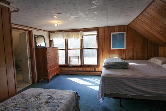 carpeted bedroom featuring vaulted ceiling, a baseboard heating unit, and wood walls