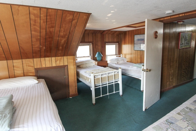 bedroom featuring wood walls, a textured ceiling, and dark colored carpet