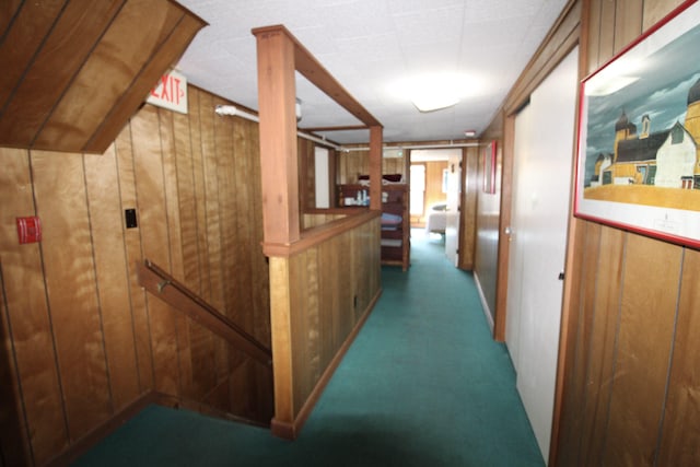 corridor featuring wooden walls and carpet flooring