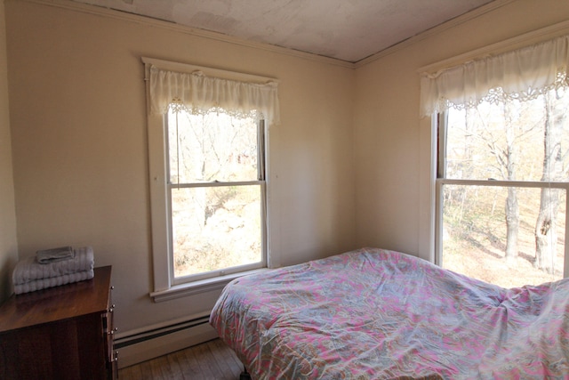 bedroom featuring crown molding, wood-type flooring, and baseboard heating