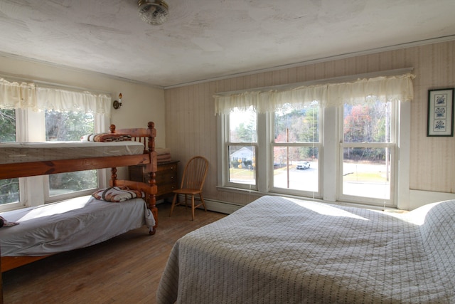 bedroom featuring ornamental molding, baseboard heating, and dark hardwood / wood-style floors