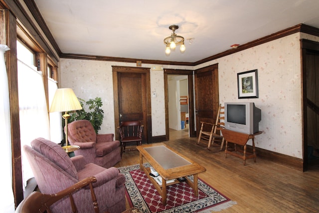 living room featuring an inviting chandelier, ornamental molding, and hardwood / wood-style flooring