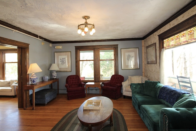 living room with ornamental molding, a chandelier, a baseboard heating unit, and hardwood / wood-style flooring