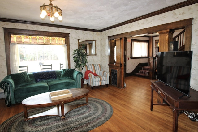 living room with crown molding, wood-type flooring, and a chandelier