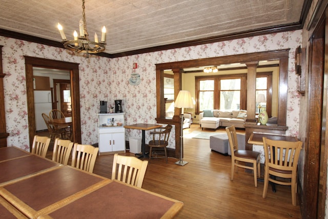 dining area with ornamental molding, wood-type flooring, and ornate columns