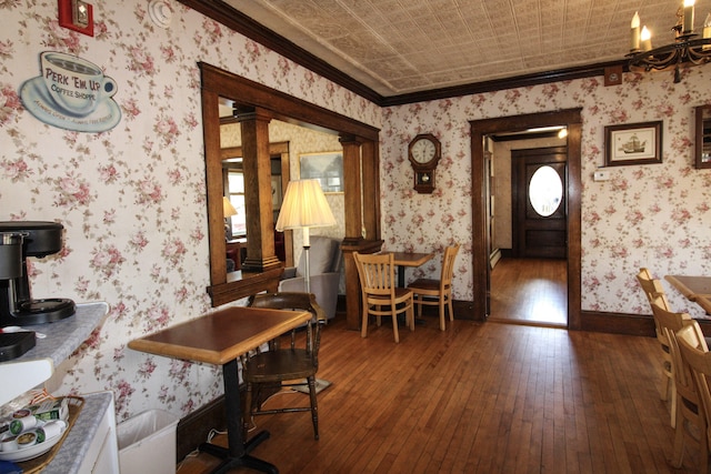 dining room featuring crown molding, hardwood / wood-style flooring, a chandelier, and decorative columns