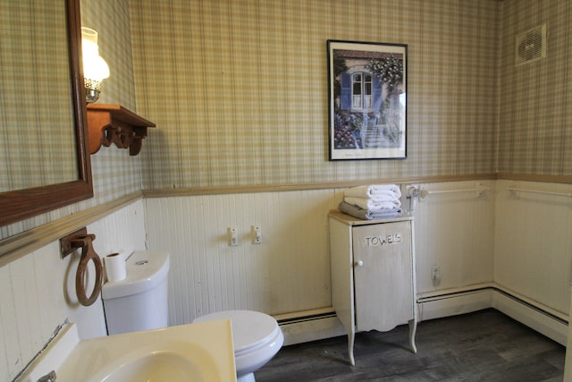 bathroom with toilet, wood-type flooring, and a baseboard heating unit