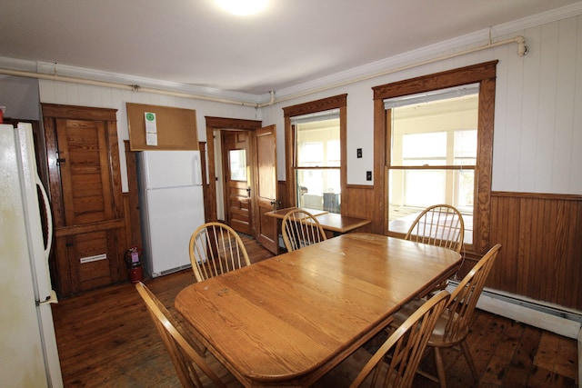 dining area with crown molding, wood walls, baseboard heating, and dark wood-type flooring