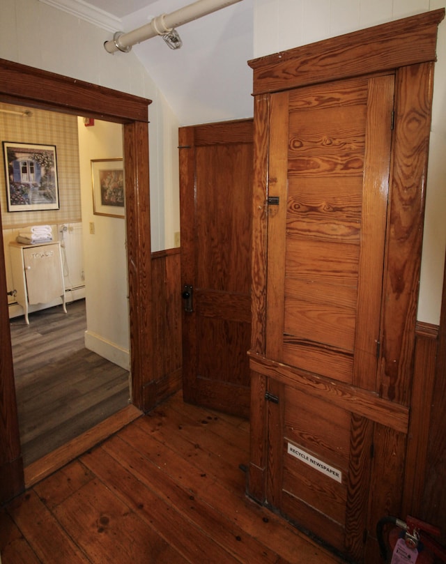 hallway featuring crown molding, wood walls, vaulted ceiling, and dark hardwood / wood-style flooring