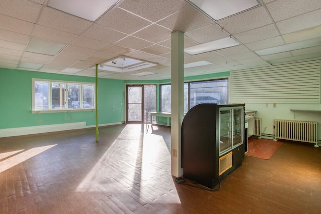 interior space featuring a drop ceiling, radiator heating unit, and dark hardwood / wood-style floors