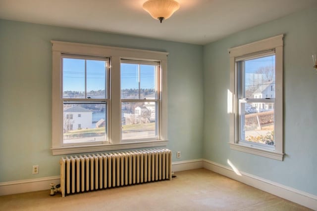 spare room with light carpet and radiator heating unit