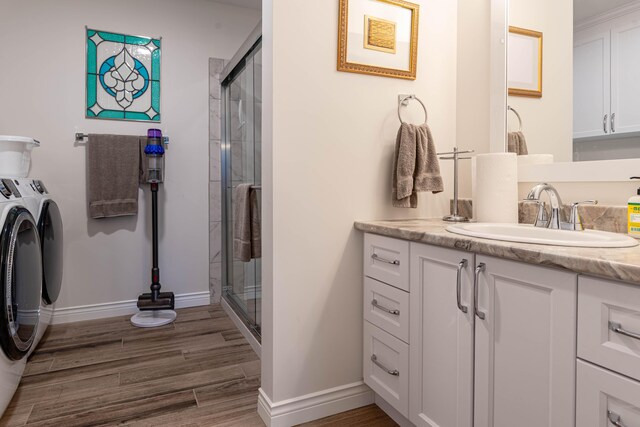 320 19th Ave Unit 101, Madawaska, ME 04756 - bathroom with washing machine and dryer, a stall shower, wood finished floors, vanity, and baseboards