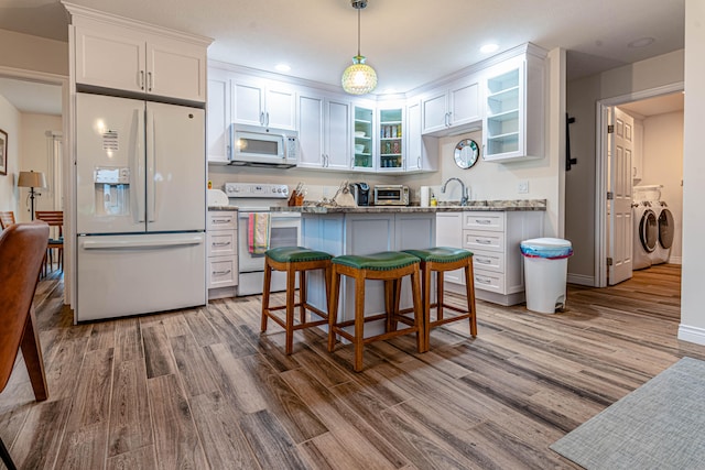 kitchen featuring pendant lighting, separate washer and dryer, white cabinets, light stone counters, and white appliances